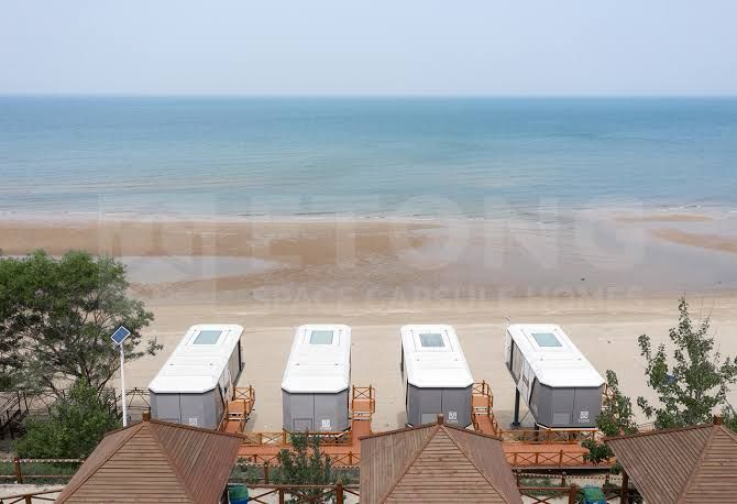 Row of capsule resort pods installed on beachfront for hospitality development
